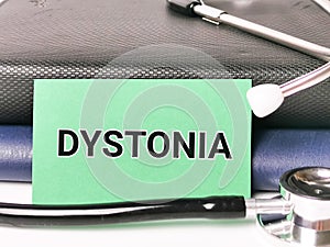 Phrase DYSTONIA written on green paper card with stethoscope and books.