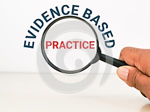 Phrase evidence based practice with hand hold magnifying glass. photo