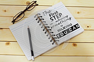 Phrase THE FIRST STEP IN ACHIEVING SOMETHING IS BELIEVING YOU CAN written on one page of a notebook. Inspirational and motivationa