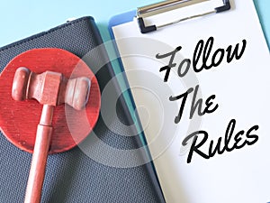 Phrase follow the rules written on notebook with a pen and gavel.