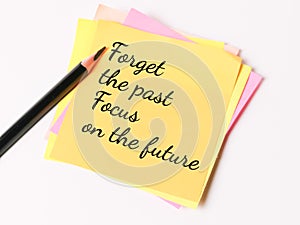 Phrase forget the past focus on the future written on sticky note with a pencil.