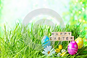 Phrase Happy Easter made of letters on a background of green grass, Easter eggs