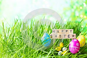 Phrase Happy Easter made of letters on a background of green grass, Easter eggs