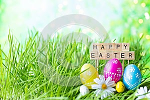 Phrase Happy Easter made of letters on a background of green grass, Easter eggs