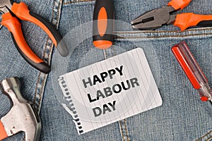 Phrase HAPPY LABOUR DAY written on white paper with hammer, screwdrivers and pliers