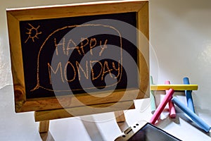 Phrase happy monday written on a chalkboard on it and smartphone, colorful chalk