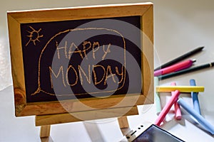 Phrase happy monday written on a chalkboard on it and smartphone, colorful chalk
