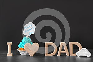 Phrase `I love dad` and cupcake on table