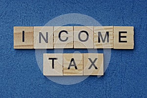 Phrase income tax in small square wooden letters