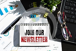 Phrase Join our newsletters written on notebook with office tools on wooden table. Motivational concept