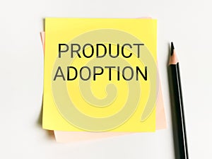 Phrase product adoption written on sticky note with a pencil.