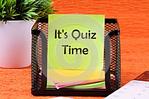 Phrase IT IS QUIZ TIME on a sticker in a stand on an orange background