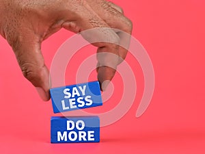 Phrase say less do more on blue wooden blocks