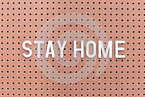 Phrase Stay home on brown pegboard, self-isolation concept, horizontal