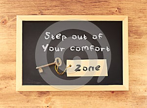 The phrase step out of your comfort zone written on blackboard