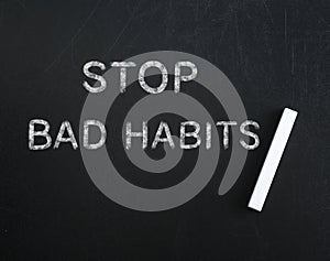 Phrase Stop Bad Habits and piece of chalk on blackboard, top view