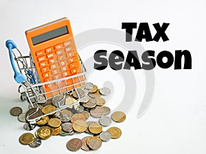 Phrase tax season with calculator,trolley and coins isolated on white background.