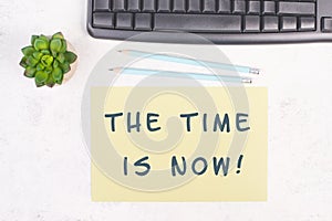 The phrase the time is now is standing on a paper, a pen, computer keyboard and a cactus, brainstorming for new business ideas
