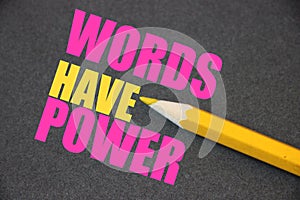 The phrase Words Have Power written with yellow pencil on texturized dark grey paper. Copywriting PR publishing business concept photo