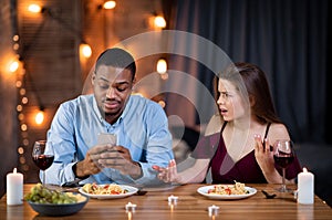 Phubbing Concept. Black Man Busy With Smartphone During Dinner With His Girlfriend