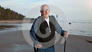 Physical activity 70s grandfather Scandinavian walking stick outdoor sport retirement hobby at beach