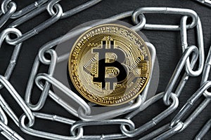 Physical Bitcoin gold coin on a convoluted shiny metal chain