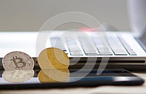 Physical bitcoins leaning on laptop