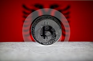 Physical silver version of Bitcoin BTC and Albania Flag on the background. Conceptual image for investors in