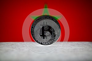 Physical silver version of Bitcoin BTC and Morocco Flag on the background. Conceptual image for investors in