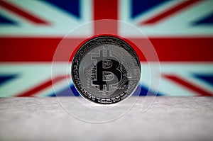 Physical silver version of Bitcoin BTC and United Kingdom Flag on the background. Conceptual image for investors in