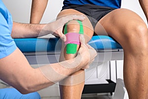 Physical therapist applying kinesio tape on male patient knee. Kinesiology, physical therapy, rehabilitation concept