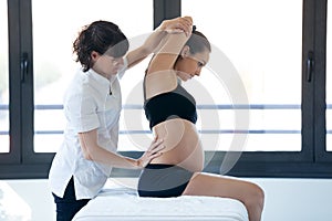 Physical therapist doing stretching to pregnant woman in a spa center