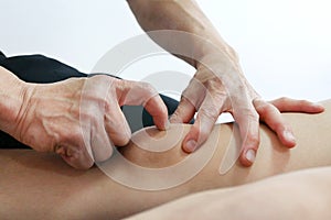 Physical therapist hands techniques treat knee on the patient leg to reduce pain