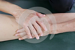 Physical therapist hands treat the knee to the patient