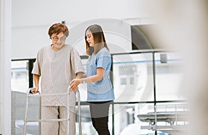 physical therapist helping senior patient in using walker during rehabilitation