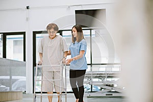 physical therapist helping senior patient in using walker during rehabilitation