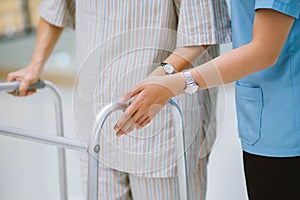 physical therapist helping senior patient in using walker during rehabilitation