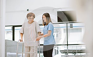 physical therapist helping senior patient in using walker during rehabilitation