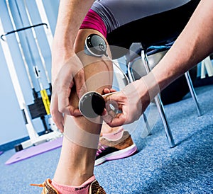 Physical therapist install electrostimulator on the muscles of the legs