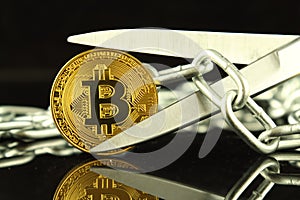 Physical version of Bitcoin, scissors and chain. Conceptual image for Blockchain Technology and hard fork term refers to a situat