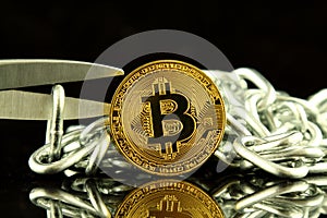 Physical version of Bitcoin, scissors and chain. Conceptual image for Blockchain Technology and hard fork term refers to a situat