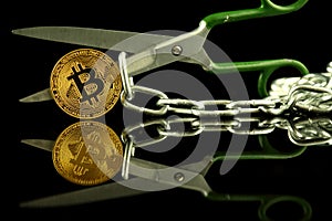 Physical version of Bitcoin, scissors and chain. Conceptual image for Blockchain Technology and hard fork term refers to a situat
