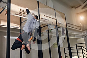Physically challenged climber performing special exercises at wooden panel