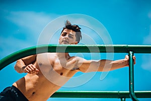 Physically fit man exercising outdoors doing triceps dips on parallel bars