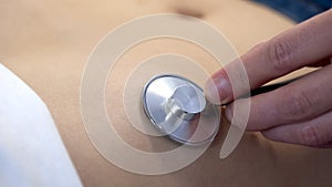 Physician auscultating female patient belly with stethoscope, health care