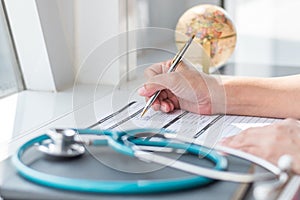 Physician doctor writing on medical health care record, patients discharge, or prescription form paperwork in hospital clinic photo