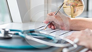 Physician doctor writing on medical health care record, patients discharge, or prescription form paperwork in hospital clinic