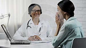 Physician informing patient about good news, showing test results on laptop