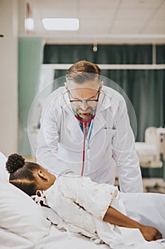 Physician listening to the heart beat of a little girl photo