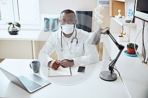 Physician in a mask posing for camera at his desk